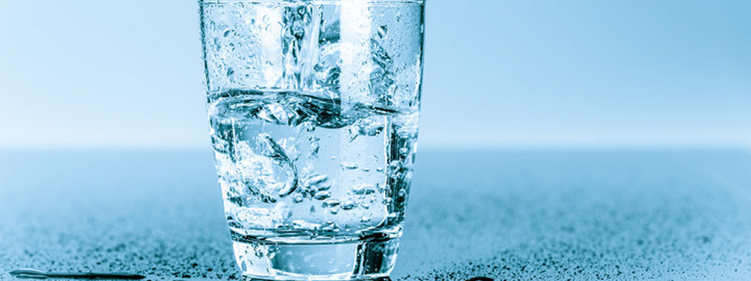 Auf einem Tisch steht ein Glas mit klarem Wasser