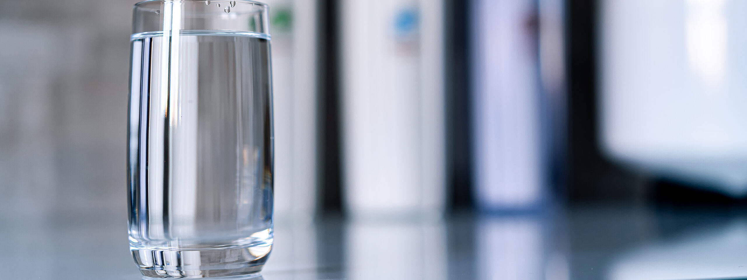 Auf einem Tisch steht ein Glas mit klarem Wasser