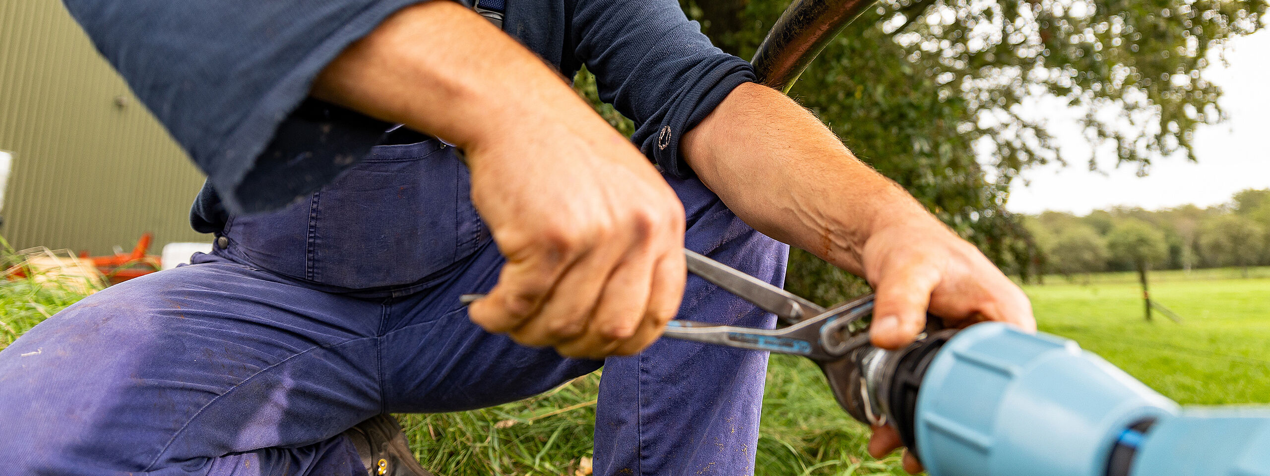 Ein Mann verarbeitet im Garten ein PP-Klemmfitting von UNIDELTA mit Hilfe einer Rohrzange